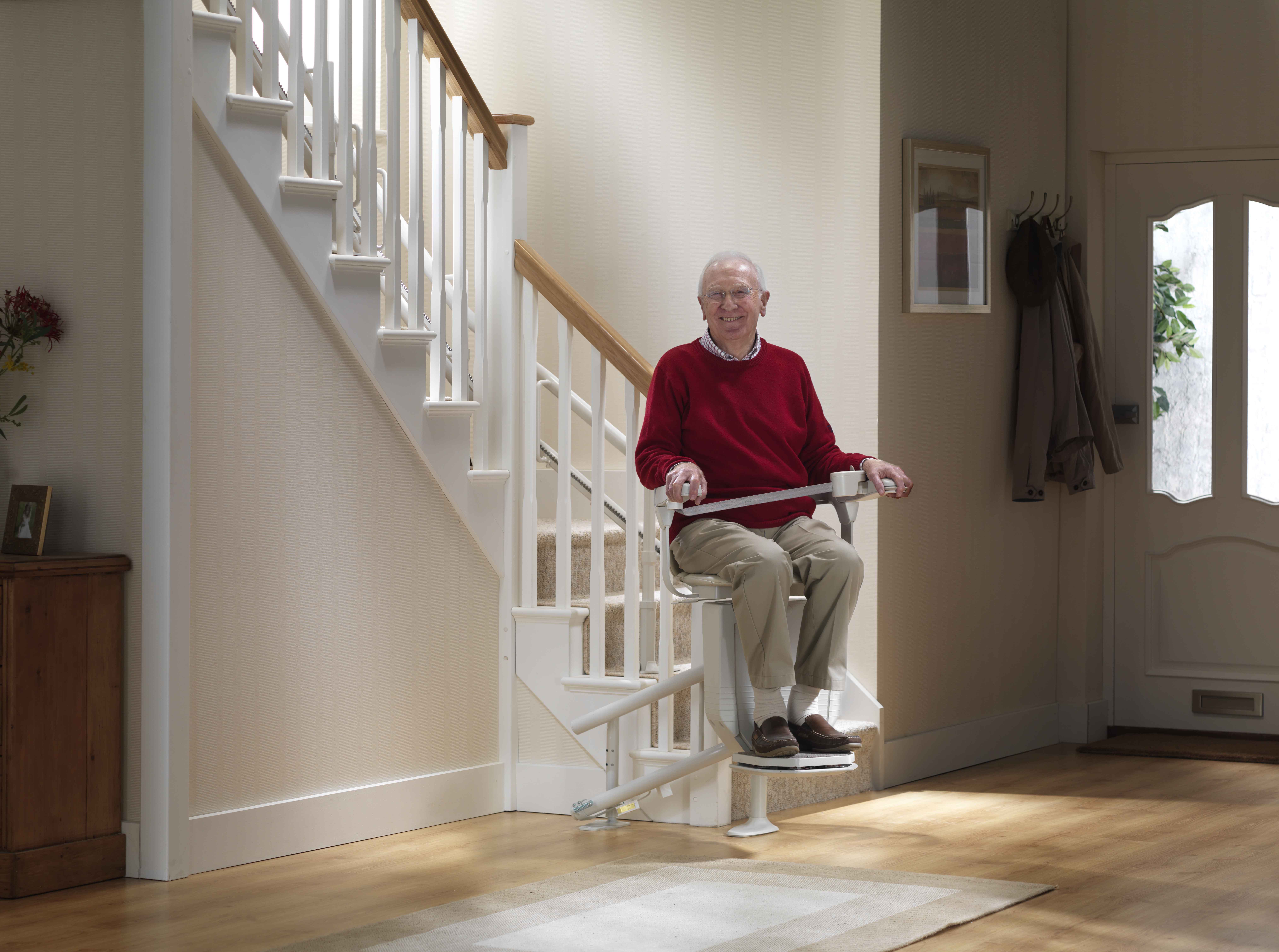 old man gliding upstairs with a stairlift