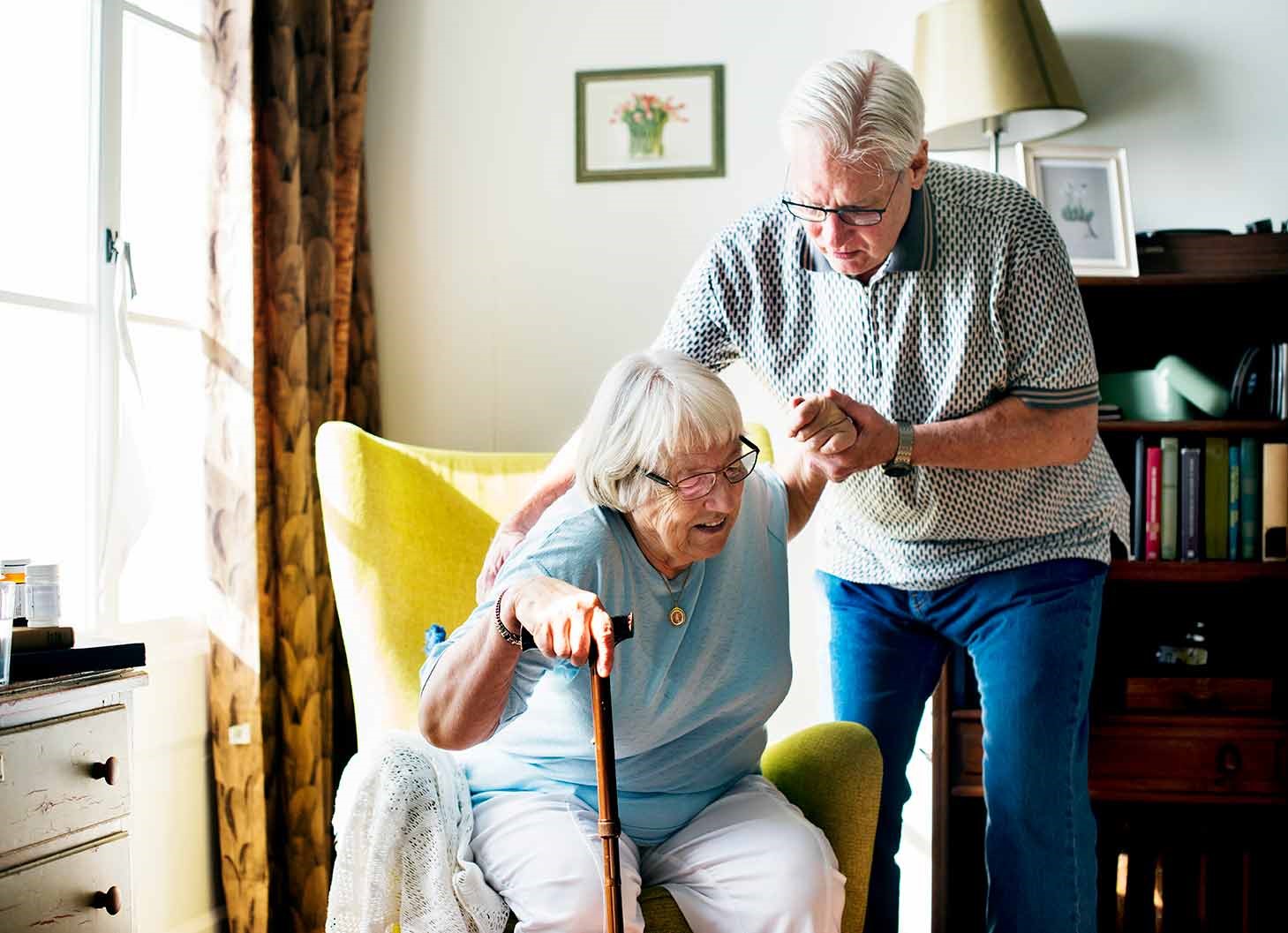 helping an elderly woman to get up of a chair