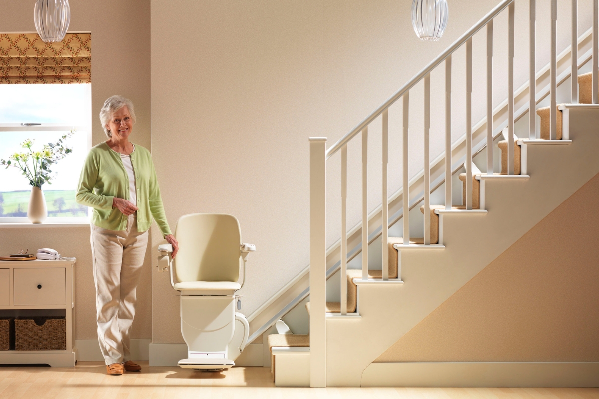 Senior woman standing happily by her Stannah stairlift

