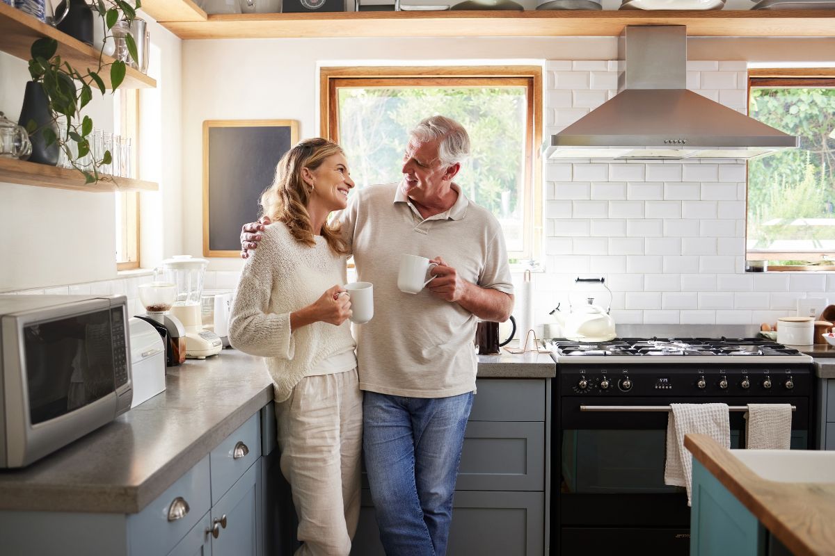 Smiling older couple enjoying coffee together in a bright modern kitchen.